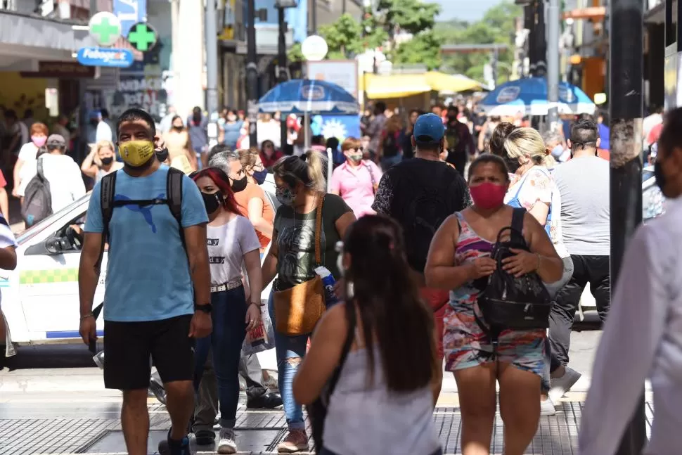 PREVENCIÓN. Un hombre y una mujer caminan por la peatonal Mendoza al 600 con el barbijo obligatorio. Entre la multitud, buscan cuidarse.