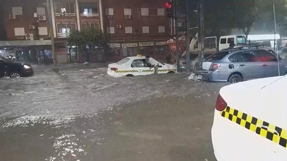 ESCAPE. Un taxista sale de su vehículo por la ventanilla para huir del agua que ingresaba. Ocurrió en la esquina de Roca y 9 de Julio.