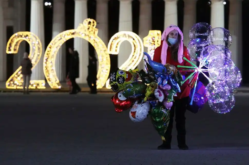 CRIMEA. Un vendedor ambulante ofrece globos para recibir el nuevo año frente a una imponente decoración.  