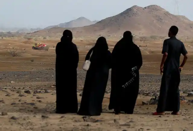 EL DAKAR EN MEDIO ORIENTE. Mujeres que visten burkas negras observan la carrera mundial entre los desiertos y las montañas de Arabia Saudita.