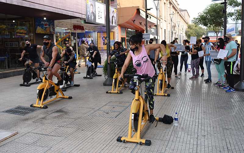 GIMNASIO EN LA PEATONAL. Los dueños de los gimnasios se manifestaron en contra de las restricciones contra el Covid-19 y llevaron sus aparatos para dar clases en espacios abiertos. Un grupo de mujeres se entrena con las bicicletas fijas en plena peatonal.