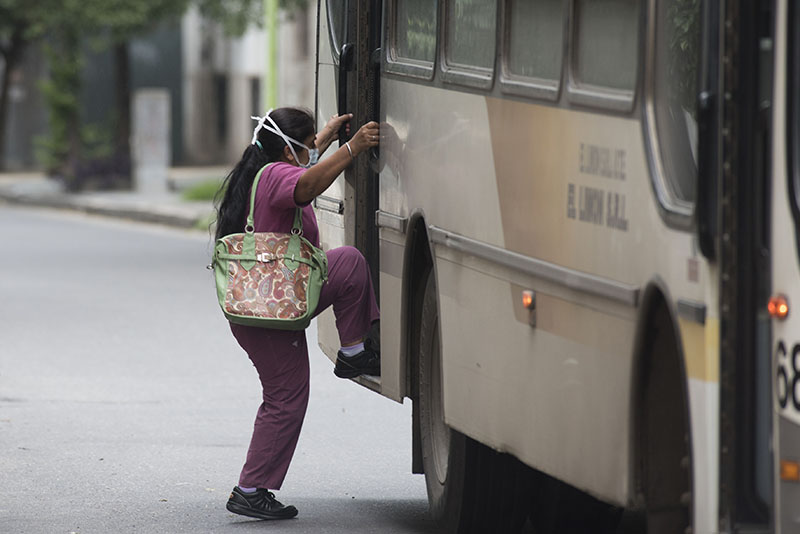 TRANSPORTE PÚBLICO EN PANDEMIA. Una mujer sube a un colectivo por la puerta trasera durante las restricciones más estrictas, a fines de marzo del 2020.