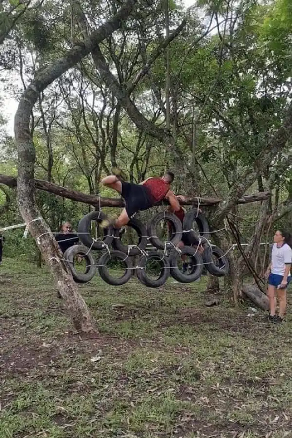 OBSTÁCULO ARTIFICIAL. Un competidor trepado en una “pared” de neumáticos y sogas, en plena competencia.