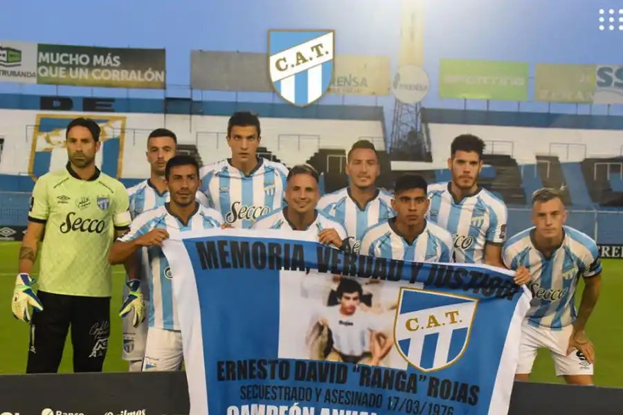 RECUERDO. Los jugadores posan con el cartel recordando a Ernesto Rojas, secuentrado y asesinado el  17 de marzo de 1976, por el terrorismo de Estado.