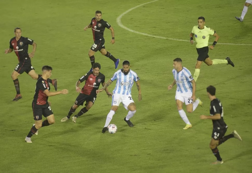 RODEADO. “Junior” Benítez aguanta la pelota ante la marca de Pablo Pérez, el delantero jugó un partido completo por primera vez desde que llegó a Atlético. 