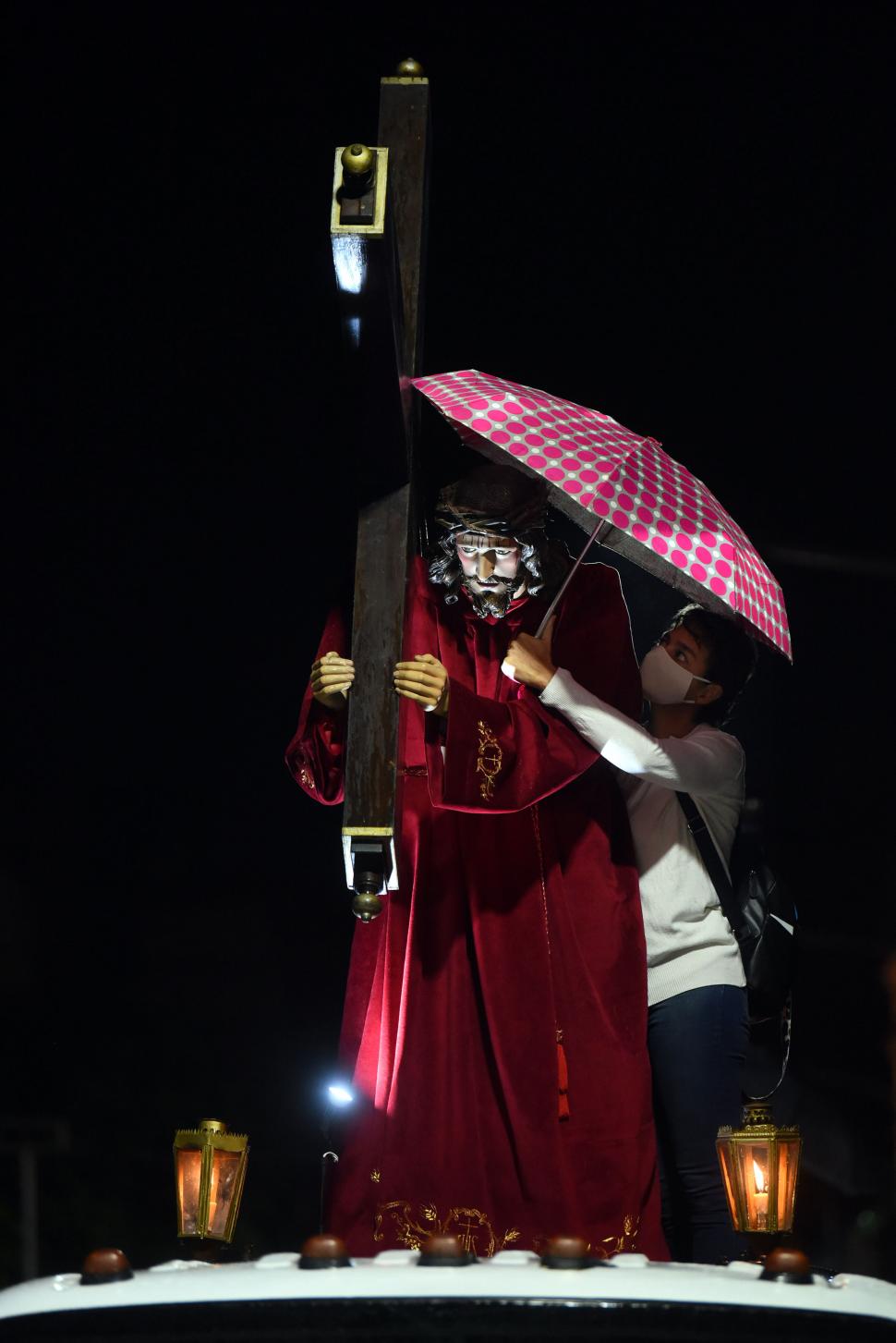 EL NAZARENO. Bajo una ténue llovizna, una devota protege bajo un paraguas la bella imagen de Cristo llevando su cruz, durante la procesión.