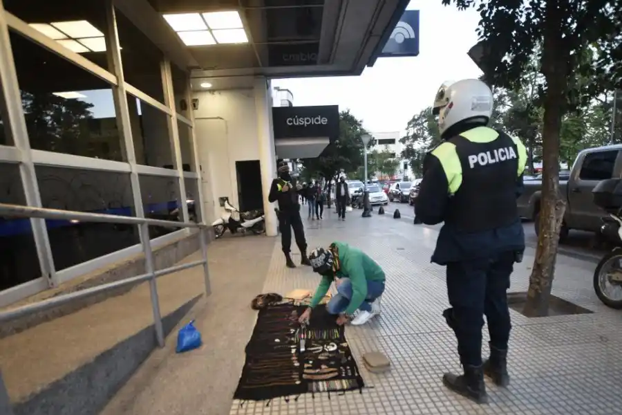 NADIE EN LAS CALLES. Dos policías esperan que un vendedor ambulante levante su mercadería del piso durante la siesta de ayer.