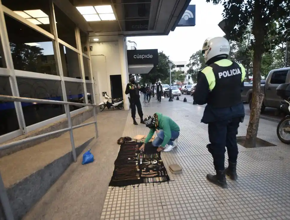 NADIE EN LAS CALLES. Dos policías esperan que un vendedor ambulante levante su mercadería del piso durante la siesta de ayer.