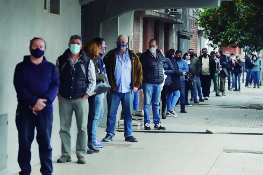 FILA. La gente esperó para vacunarse en la vereda del club Caja Popular. 