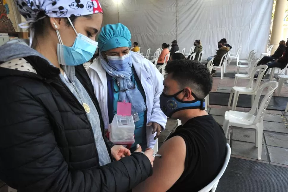 VACUNADO. Un joven tucumano recibe la primera dosis suministrada por una enfermera en uno de los nodos de vacunación. 