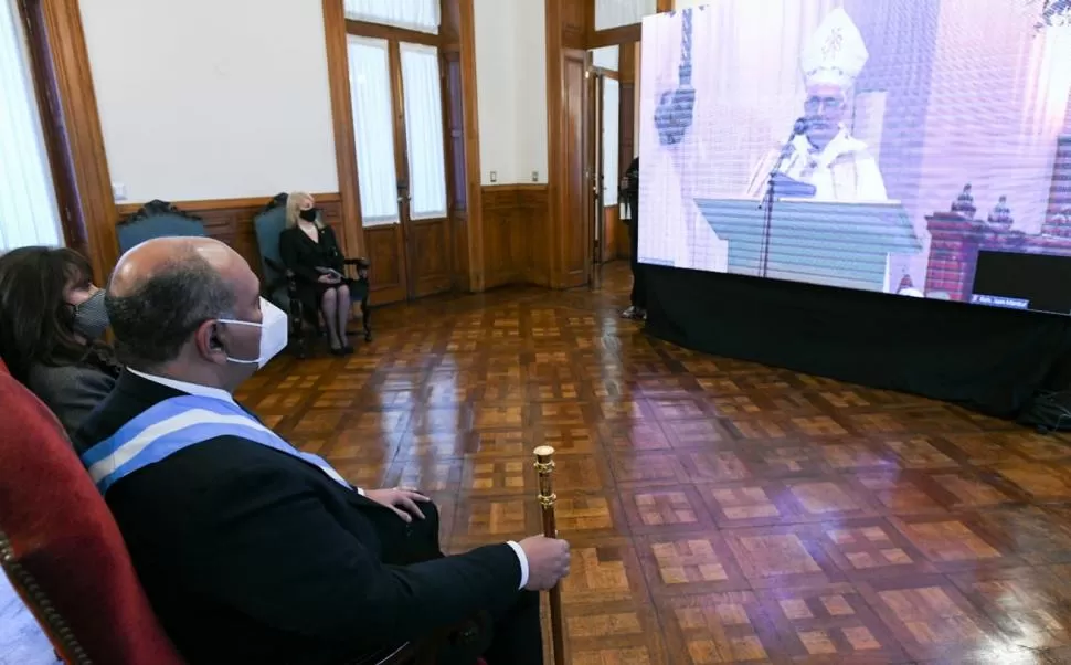 EN CASA DE GOBIERNO. El gobernador Juan Manzur mira el oficio de la misa en pantalla gigante.  