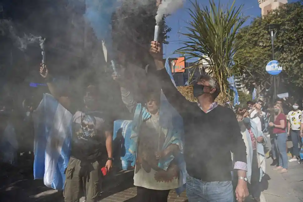 ENCENDIDOS. Tres manifestantes prenden bengalas que despiden humo celeste y blanco en la movilización contra el Gobierno. 