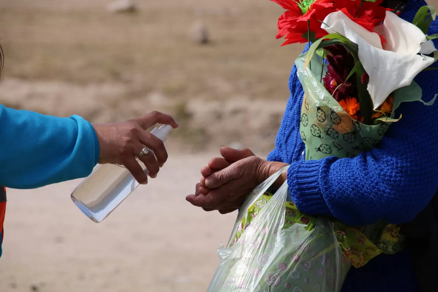CAMPAÑA DE PREVENCIÓN. Una agente ayuda a una ciudadana a sanitizar sus manos. Foto de Facebook Municipalidad de Tafí del Valle