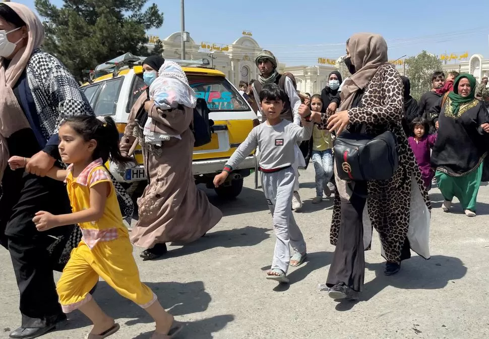 RETIRADA. Mujeres con sus hijos se encaminaban ayer hacia al aeropuerto internacional Hamid Karzai, en Kabul, para tratar de salir del país.  