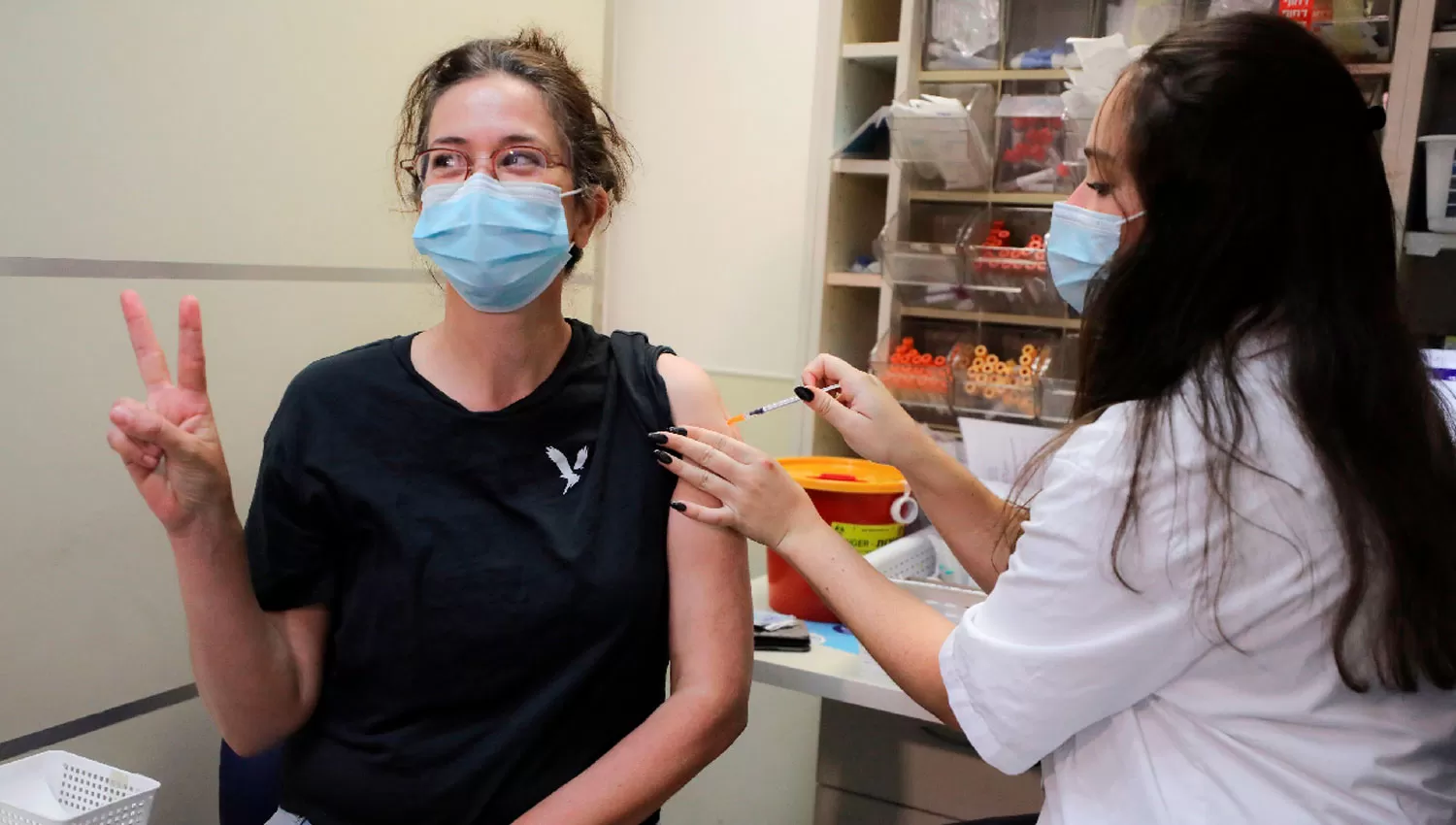 DEDOS EN V. Una mujer posa en un vacunatorio de Jerusalem luego de recibir la tercera dosis de la vacuna contra la covid-19..