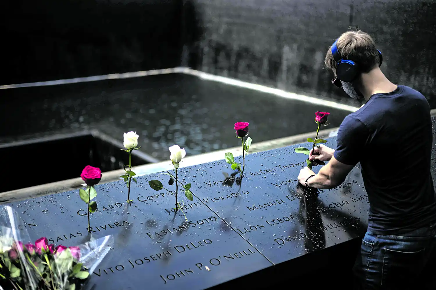 LOS NOMBRES. Un joven coloca rosas en el monumento donde figuran las víctimas de los atentados.