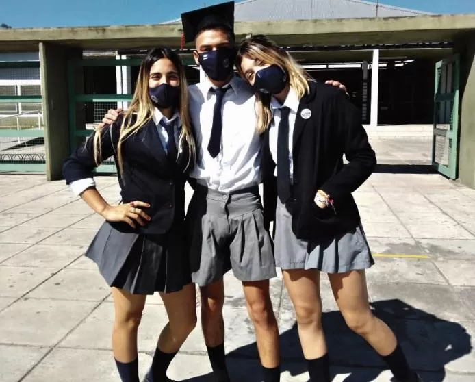 “LA ROPA NO TIENE GÉNERO”.  Luis Villafañe vestido con la pollera del uniforme, posa frente a su escuela en Alberdi flanqueado por sus compañeras.  