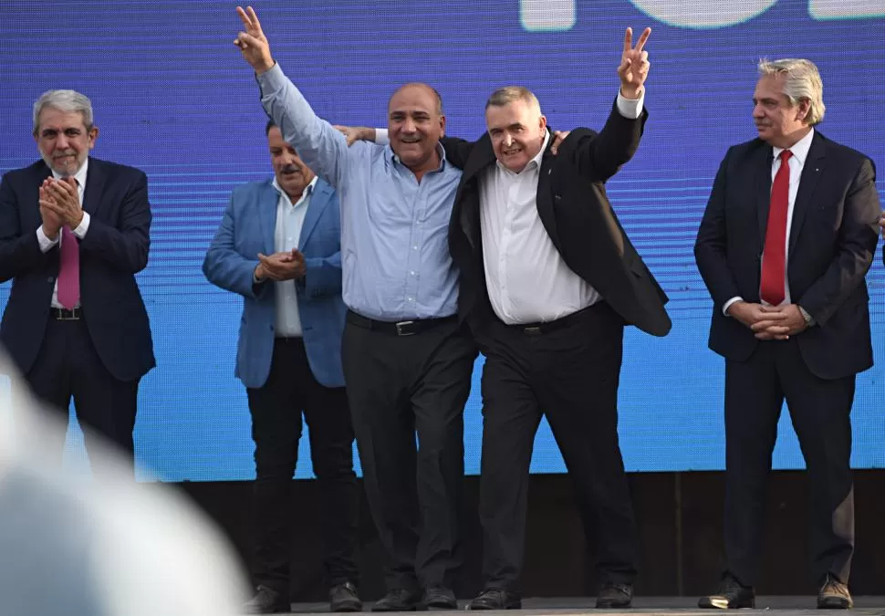 ABRAZO. Juan Manzur y Osvaldo Jaldo se abrazan con los dedos en “v” ante la mirada del presidente. 