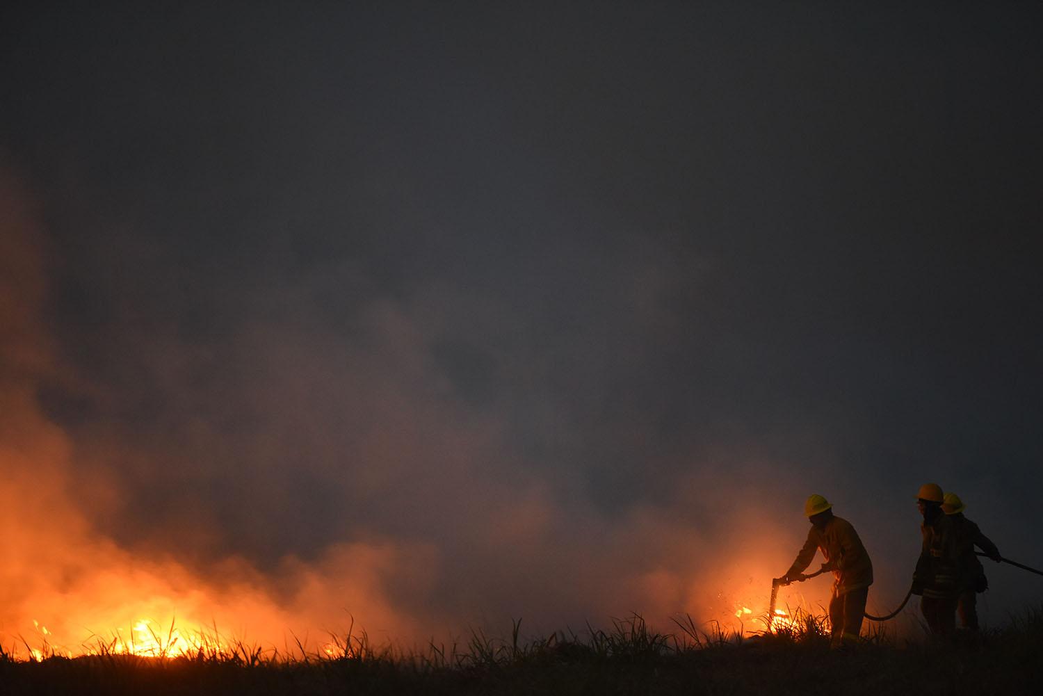 UNA DURA LUCHA QUE SE PROLONGÓ DURANTE TODA LA JORNADA, INCLUSO HASTA EL ANOCHECER. Los bomberos arrojan agua a un foco de incendio para apagar las llamas en un pequeño campo de caña de Las Cejas.
