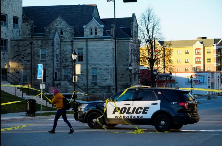 Una persona pasa junto a un coche de policía que bloquea Main Street la mañana después de que un coche atravesó un desfile festivo en Waukesha, Wisconsin, EE. UU., El 22 de noviembre de 2021. REUTERS / Cheney Orr