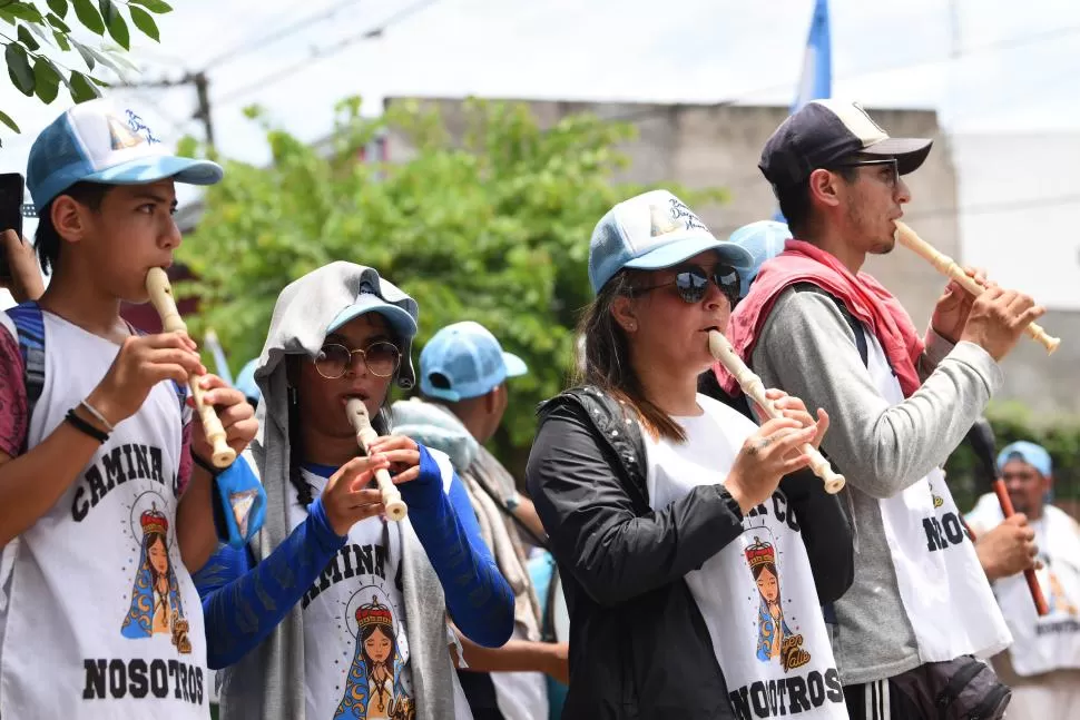 CORO DE FLAUTAS. Jóvenes del barrio Los Pocitos animan el paso de la imagen con flautas y bombos. 