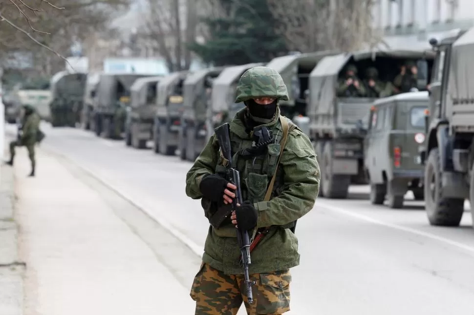 FRONTERA. Militares armados esperan en vehículos del ejército ruso frente a un puesto de guardia ucraniano. REUTERS 