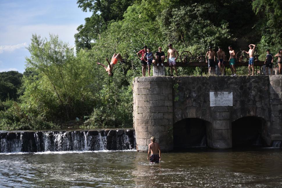 DESDE LO ALTO. Un joven se tira al río haciendo piruetas desde una plataforma que está cinco metros de altura en El Badén. El resto del grupo lo mira y espera su turno. la gaceta / fotos de osvaldo ripoll - antonio ferroni