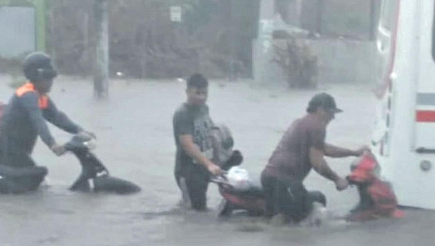 MEJOR A PIE. Por la fuerza del agua, los motociclistas decidieron cruzar las calles caminando. 