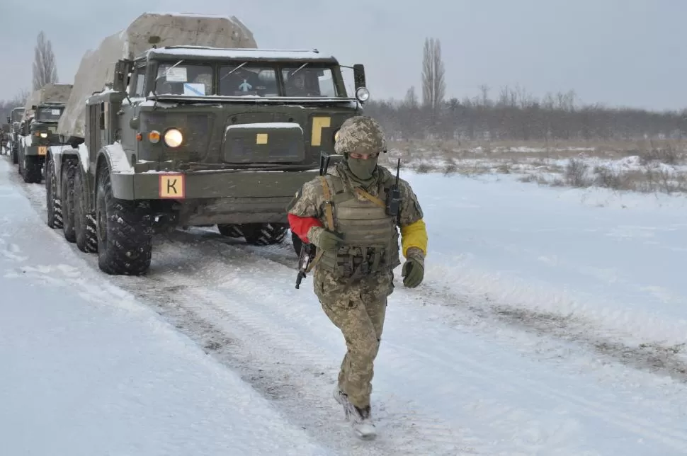EJERCICIO. Un soldado ucraniano camina en medio de la nieve frente a un convoy de vehículos pesados, en medio de una maniobra en la frontera. REUTERS 