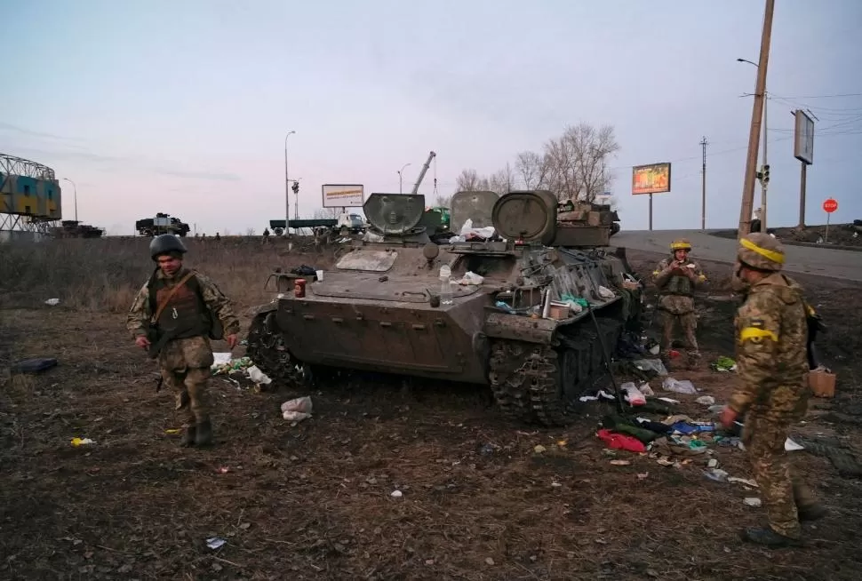 TANQUE INSERVIBLE. Los militares ucranianos están junto a un vehículo blindado destruido, que dijeron pertenecía al ejército ruso, en las afueras de Kharkiv, Ucrania. 