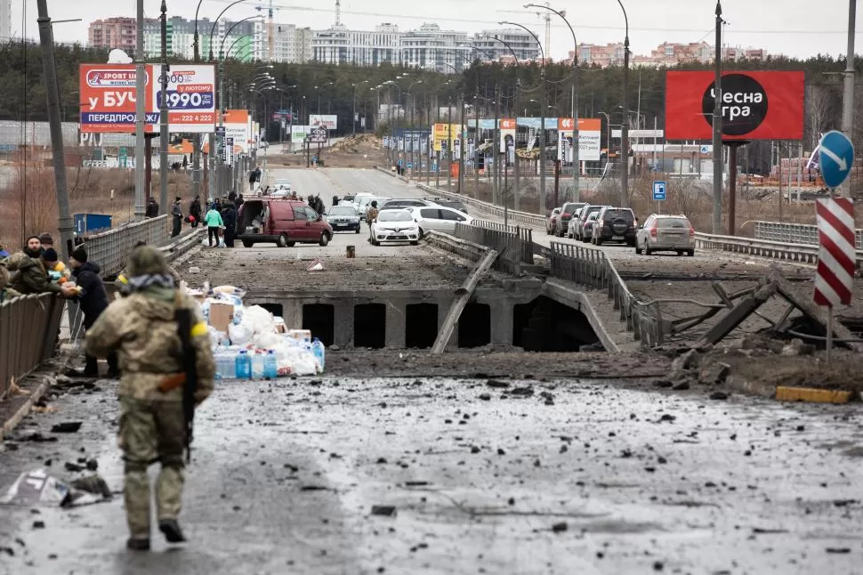 DESTRUCCIÓN. Los evacuados que huyen del conflicto bélico entre Ucrania y Rusia, cruzan un puente destruido en la ciudad de Irpin en la región de Kiev, la capital ucraniana. dfdfdfdfdf