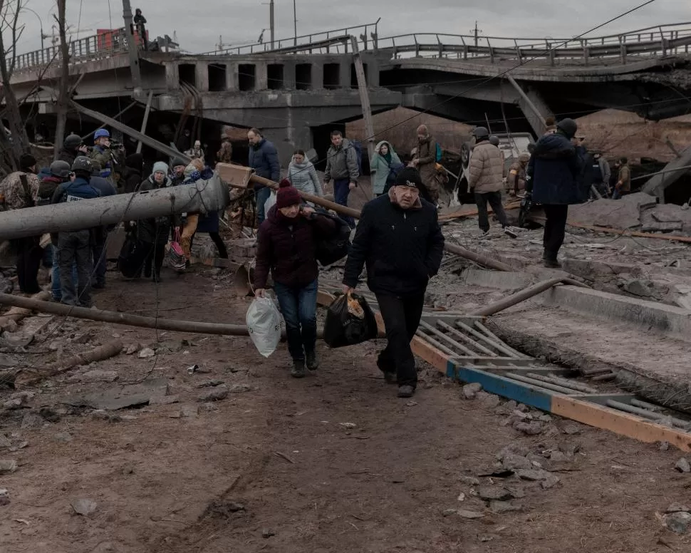 EL ÉXODO. La gente cruza un puente destruido mientras intenta salir de la ciudad de Irpin, cerca de Kiev. reuters