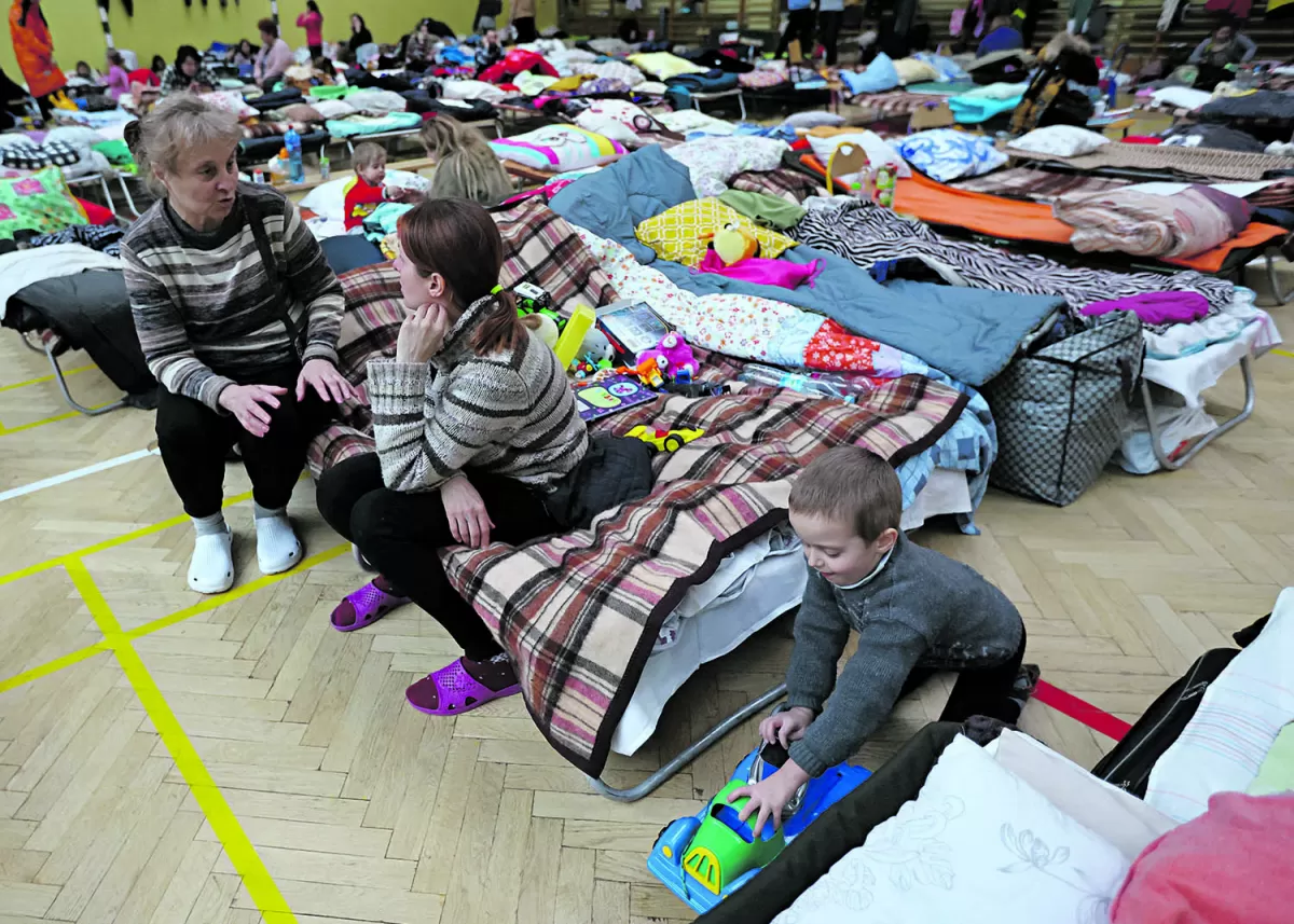 APOYO MUTUO. Mujeres y niños comparten lugar en el gimnasio de una escuela, convertido en un centro de refugiados, en Przemysl, Polonia. 