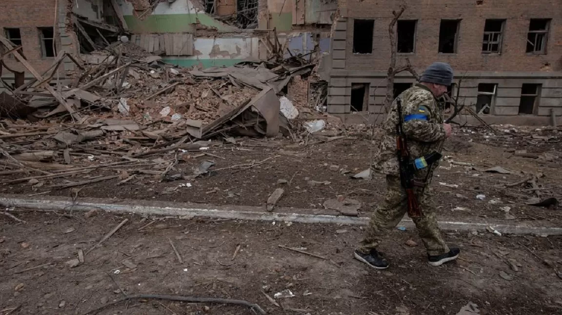 Un miembro del servicio ucraniano pasa frente a un edificio destruido por los bombardeos. Foto de Reuters