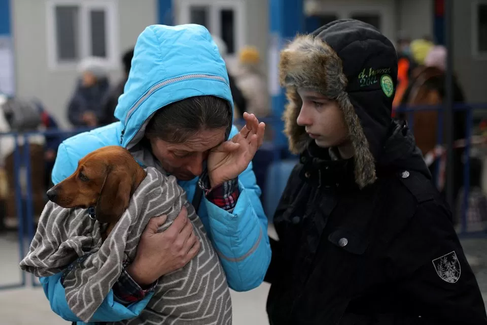 Una mujer ucraniana llora mientras sostiene a su perro, luego de su llegada a Rumania. Foto de Reuters