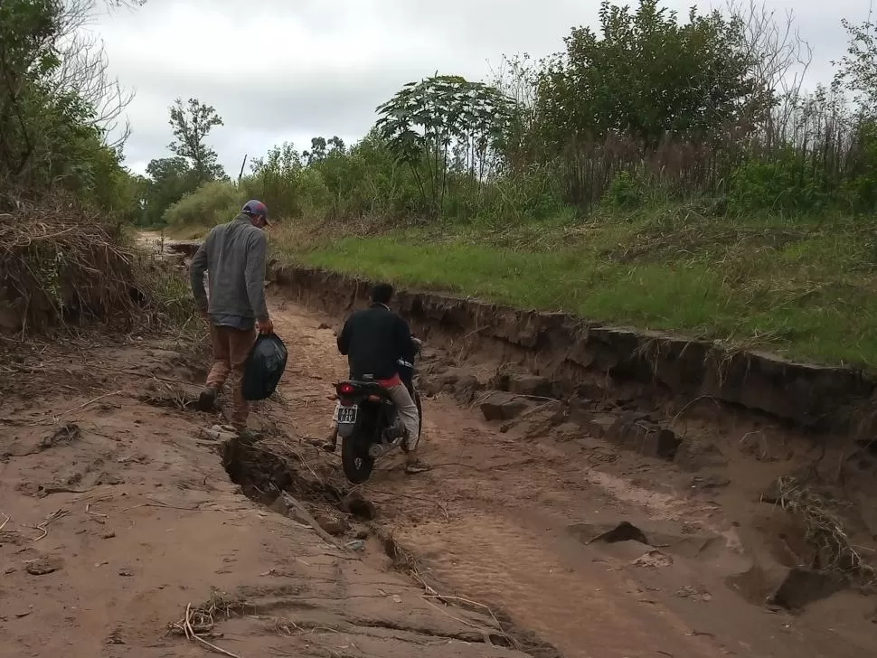 PASO VEDADO. Los pobladores intentan atravesar lo que queda del camino, convertido en una especie de lecho de río.  
