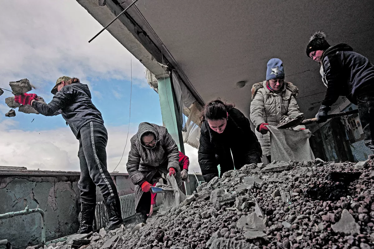 ESCUELA. Un grupo de mujeres retira los escombros de una escuela, tras un ataque ruso en la ciudad de Kharkiv. 