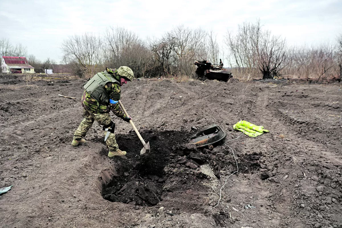 TRISTE TAREA. Un soldado ucraniano entierra los restos de un soldado ruso, en la aldea de Lukianivka, recientemente recuperada por el ejercito local.