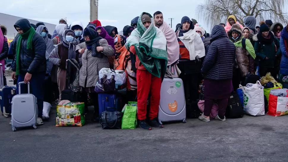 CON LO PUESTO. A la espera de un colectivo que los lleve a un centro de refugiados en Polonia, los que huyen cargan con sus pocas pertenencias.  