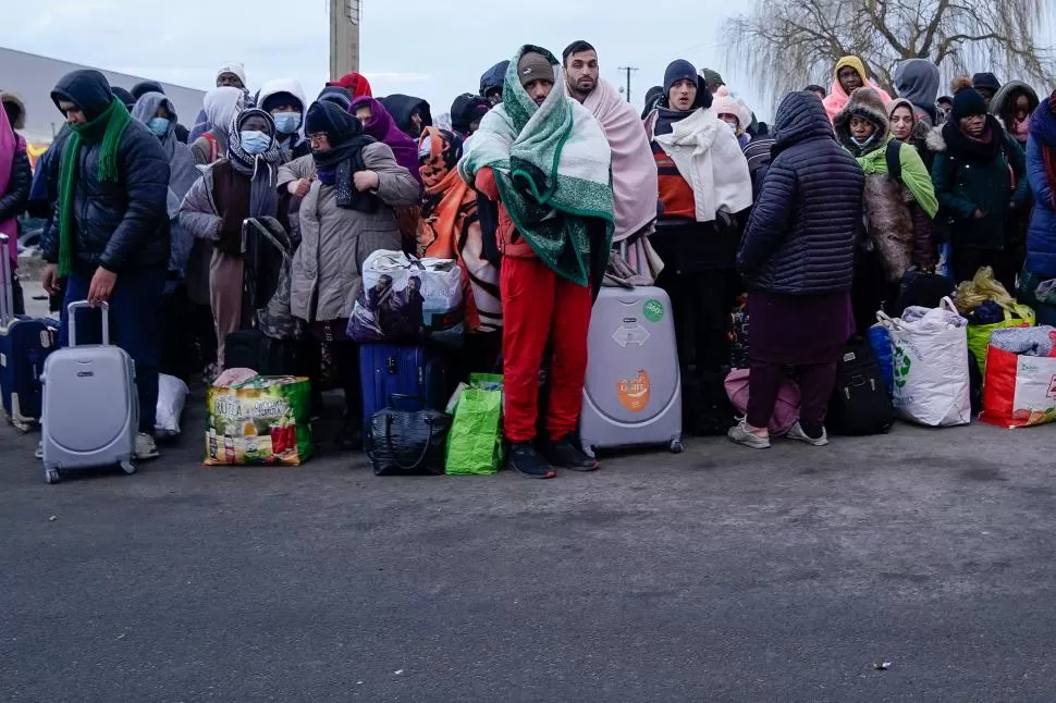 CON LO PUESTO. A la espera de un colectivo que los lleve a un centro de refugiados en Polonia, los que huyen cargan con sus pocas pertenencias.  