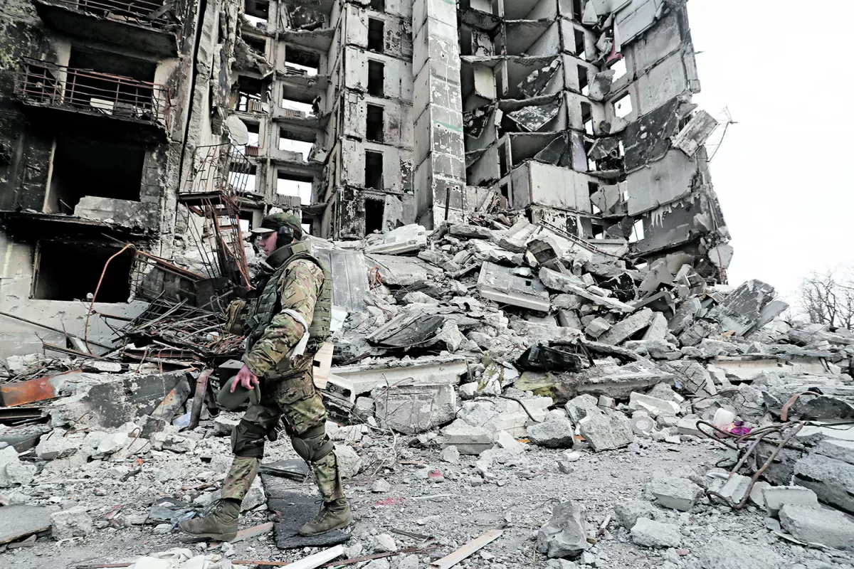 RUINAS. Un integrante de las tropas pro rusas en Ucrania pasa junto a los restos de un edificio de departamentos, en la asediada ciudad portuaria de Mariupol, que continúa bajo intenso fuego de los bombardeos rusos.