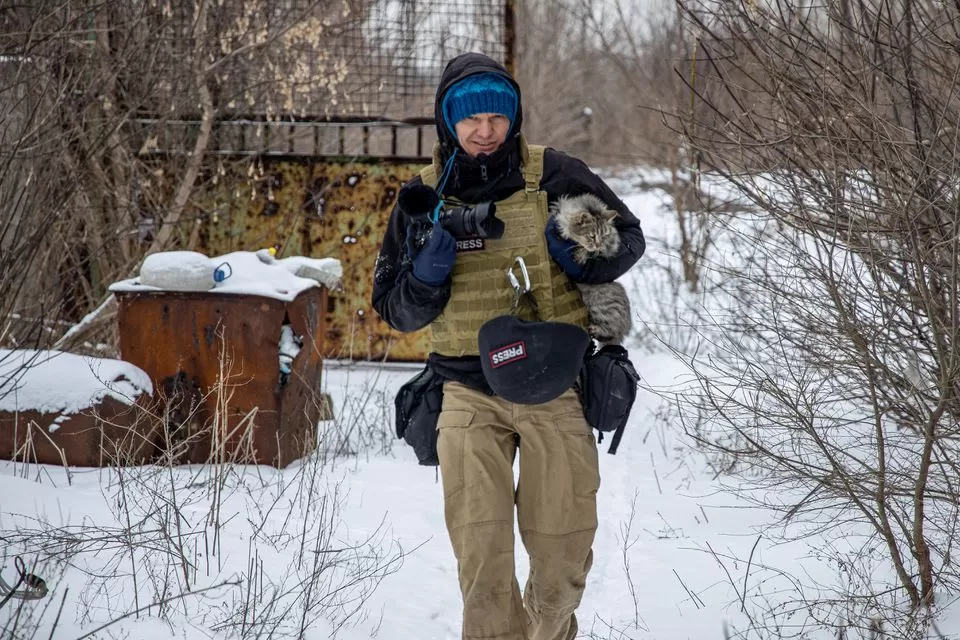 El fotógrafo ucraniano Maksim Levin lleva un gato cerca de la línea de separación de los separatistas respaldados por Rusia en la región de Donetsk, Ucrania. (reuters)