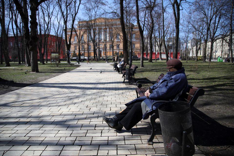 Una mujer se sienta en un banco en un parque, en Kiev. Reuters