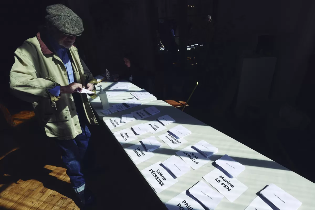 VOTACIÓN ABIERTA. Un votante toma su boleta de una de las pilas expuestas sobre la mesa electoral, en París. 