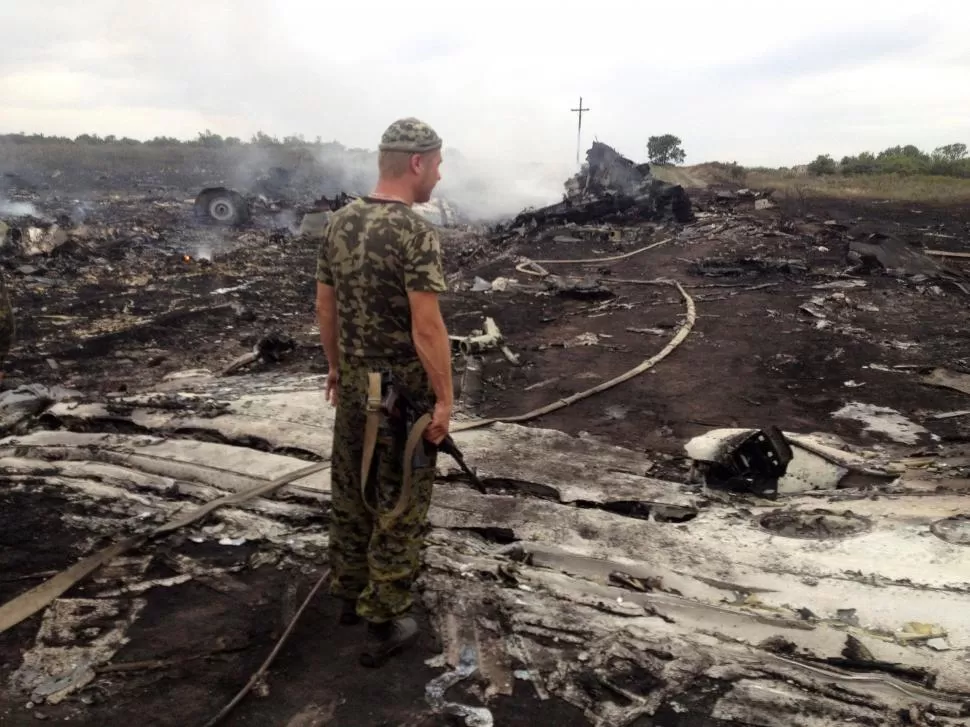 LA AERONAVE QUEDÓ REDUCIDA A ESCOMBROS. Un soldado observa los restos del avión que fue derribado por un misil ruso y causado la muerte de casi 300 personas. 