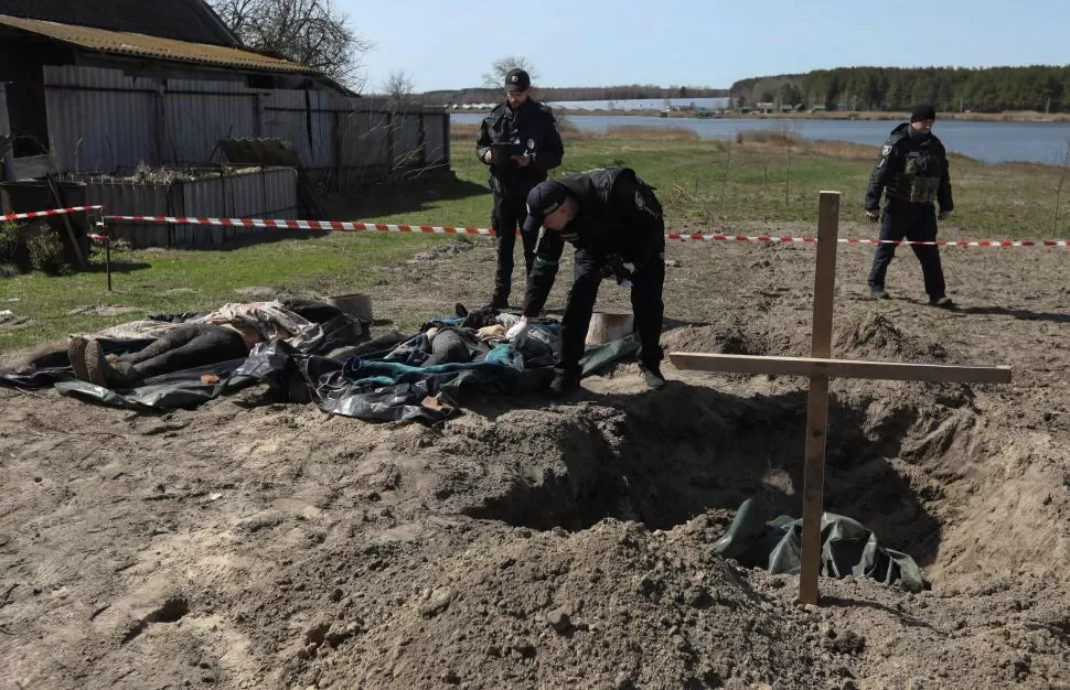 CERCA DE KIEV. Forenses ucranianos revisan cuerpos de civiles, exhumados de una fosa en la villa de Vablia. 