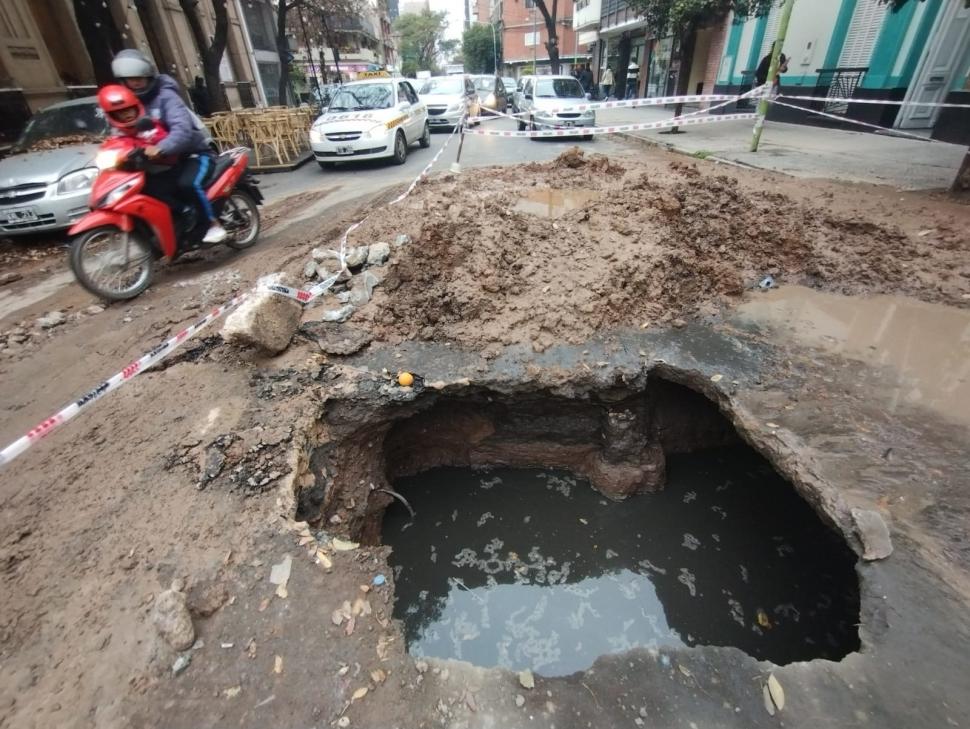 CRUCE RIESGOSO, Una motocicleta pasa por la frágil zona de pavimento cercana al agujero. 