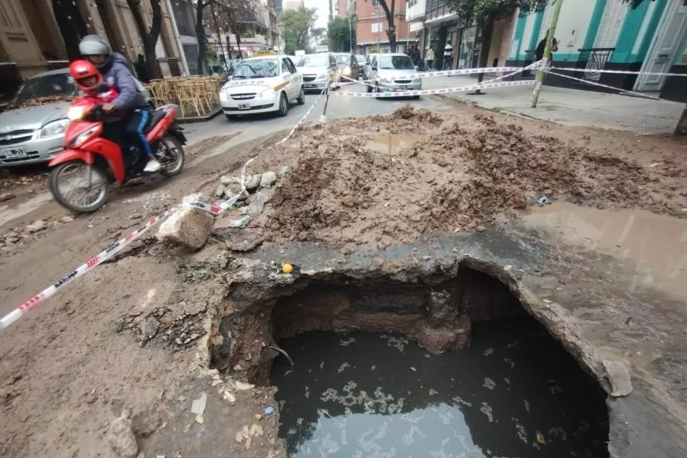 CRUCE RIESGOSO, Una motocicleta pasa por la frágil zona de pavimento cercana al agujero. 