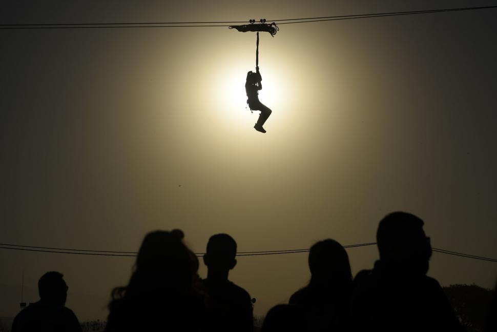 A MITAD DE CAMINO. Una niña recorre de un extremo al otro de la Expo por el aire, sujetada a la tirolesa y bajo los rayos del sol.