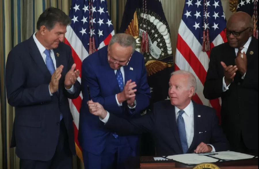  El presidente de los EE. UU., Joe Biden, le tiende la pluma al senador de los EE. UU. Joe Manchin (D-WV) mientras el líder de la mayoría del Senado, Chuck Schumer (D-NY), y el látigo de la mayoría de la Cámara de los EE. UU., James Clyburn (D-SC), observan después de que Biden firmó 